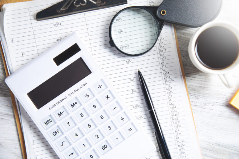 Calculator and magnifying glass on financial paperwork